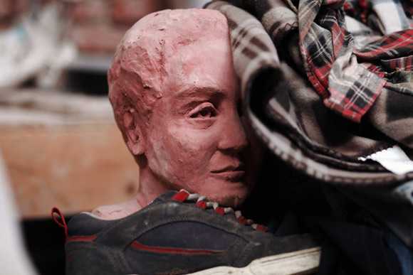 A clay head lost in a pile of clothing.